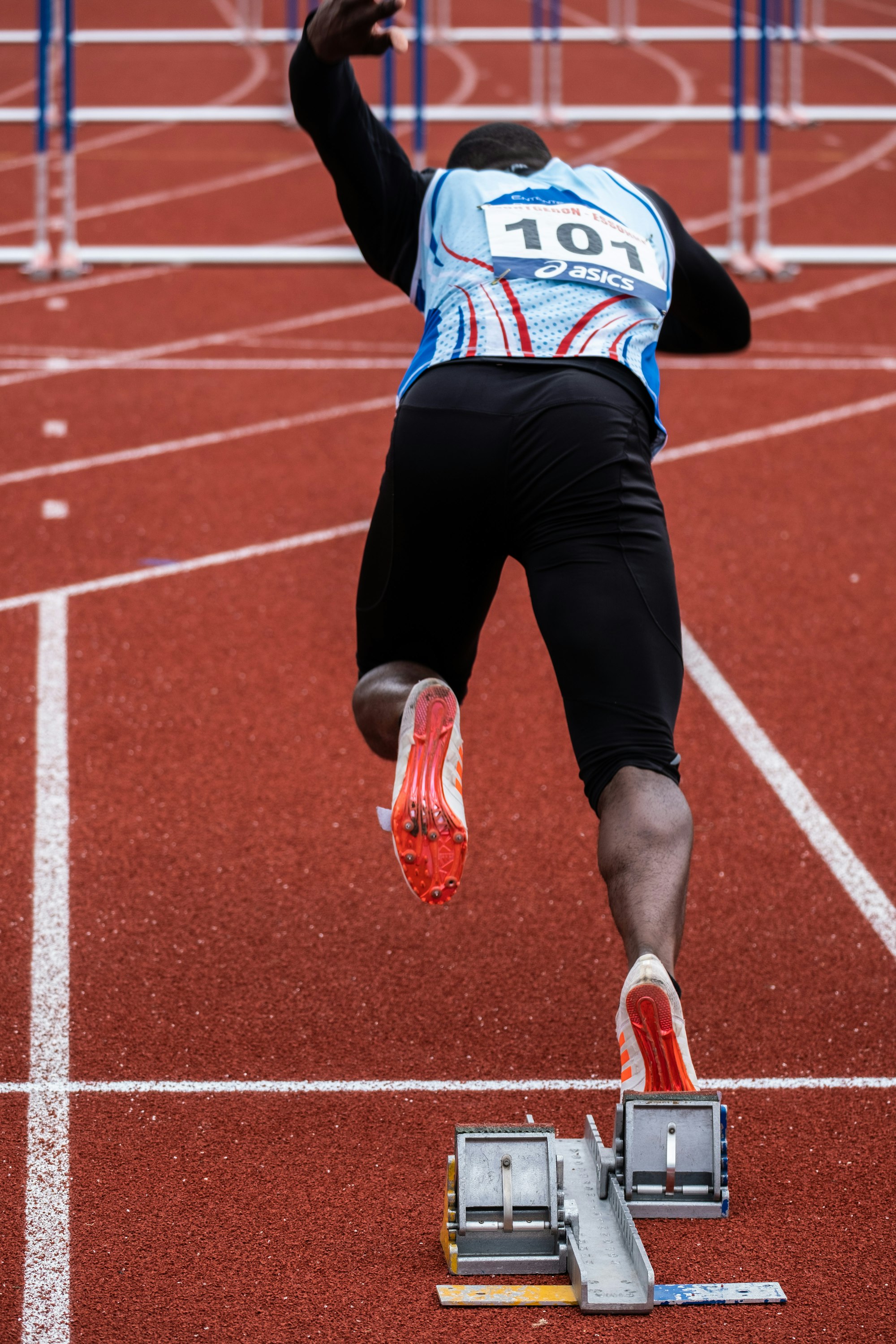 A sprinter set in the starting blocks on a red athletics track